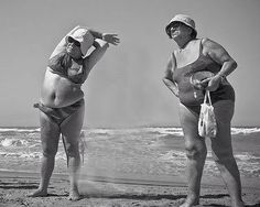 two women in bathing suits standing on the beach