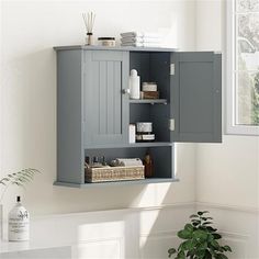 a gray cabinet is hanging on the wall next to a potted plant