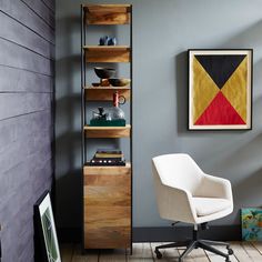 a room with a chair, bookshelf and pictures on the wall