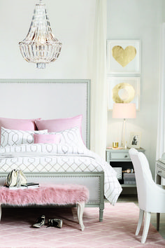 a white bed sitting next to a desk with a laptop on top of it and a chandelier hanging from the ceiling