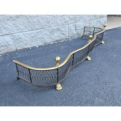 two metal beds sitting on the side of a road next to a wall and sidewalk