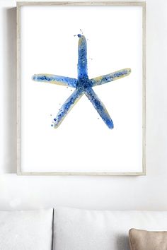 a blue starfish is hanging on the wall above a white couch in a living room