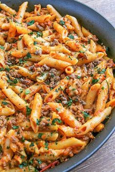 pasta with meat and sauce in a pan on a wooden table, ready to be eaten