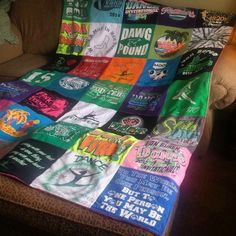 a couch with a blanket on top of it that is covered in t - shirts