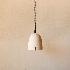 a white light hanging from a black cord on a wall next to a lamp shade