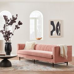 a living room with a pink couch and black vase