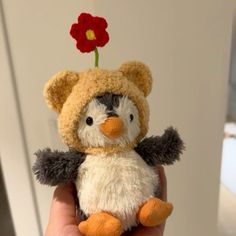 a small stuffed penguin with a flower on its head