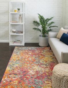 a living room with a couch, book shelf and rug on the floor in front of a white brick wall