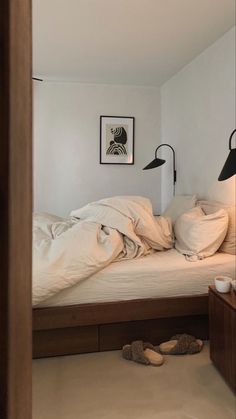 an unmade bed sitting in a bedroom next to two lamps on either side of the bed