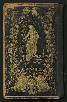 an old black book with gold foil on the front and back cover, depicting a woman surrounded by flowers