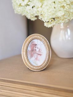 a photo frame sitting on top of a wooden table next to a vase with flowers