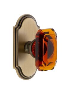 an orange glass door knob on a brass plated cabinet or drawer handle, viewed from the front