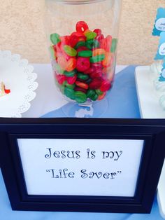 a glass jar filled with gummy bears sitting on top of a blue table cloth