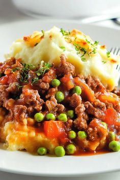 a white plate topped with mashed potatoes and meat covered in gravy next to a fork