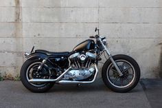 a black and silver motorcycle parked next to a cement wall on the side of a road