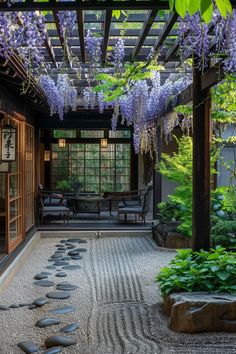 a japanese garden with purple flowers hanging from the pergolated roof and rocks on the ground