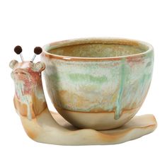 a ceramic cup and saucer shaped like a giraffe with two pins sticking out of it