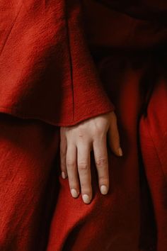 a person with their hand on the red cloth