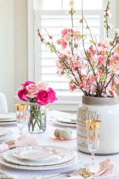 a white table topped with pink flowers and plates