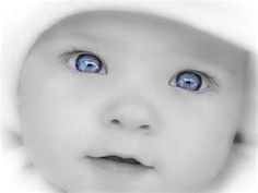 a baby with blue eyes is looking up at the camera while wearing a white hat