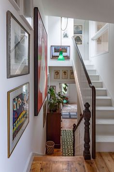 a staircase with pictures on the wall and paintings on the walls above it, along with potted plants