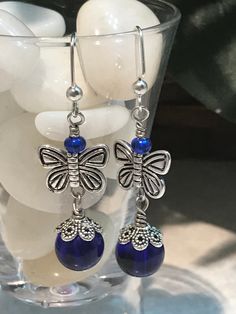 These beautiful drop earrings are meant for pierced ears. Crafted with nickel free iron fishhook ear wires, blue glass beads and silver butterflies, these are sure to please! Give as a little gift or keep for yourself! Drop length is 1 1/2 inches  color may slightly vary due to photographic lighting sources or your monitor settings Blue Butterfly Earrings, Silver Butterflies, Geode Necklace, Earrings Bead, Lava Bracelet, Agate Pendant Necklace, Blue Butterflies, Fairy Jewelry, Moon Pendant Necklace