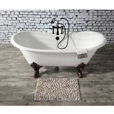 a white bath tub sitting on top of a wooden floor next to a brick wall