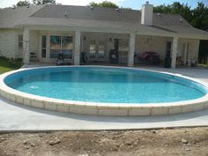 a large swimming pool in the middle of a yard with a house in the background