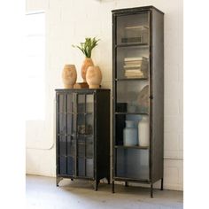 two tall black cabinets with glass doors and vases on each shelf in front of them