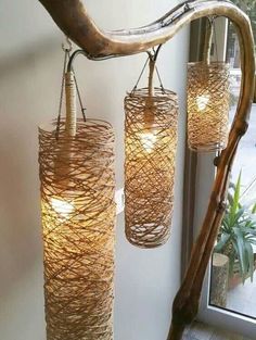 three light fixtures hanging from a wooden branch in front of a window with a mirror behind them