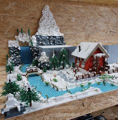 a lego model of a house in the middle of a snow covered yard and pond