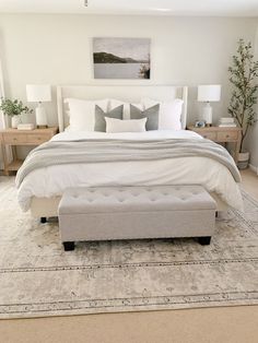 a bed with white sheets and pillows in a bedroom