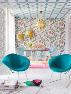 two chairs and a table in front of a wallpapered dining room with flowers on it