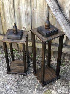 two wooden side tables sitting next to each other in front of a fenced area