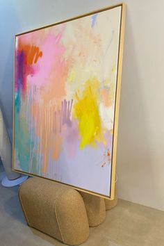 an abstract painting is on display in a room with white walls and beige flooring