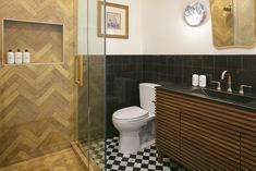 a bathroom with black and white checkered flooring, wooden cabinetry, and a glass shower door