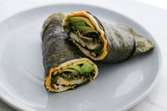 a burrito on a plate with avocado and other toppings