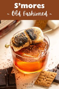 an old fashioned drink with marshmallows and chocolate on the side, next to some crackers