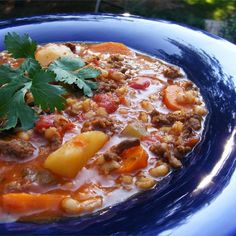 a blue bowl filled with soup and vegetables