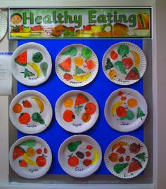 paper plates with different fruits and vegetables painted on them in front of a bulletin board