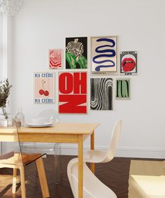 a dining room table and chairs in front of a wall with art hanging on it