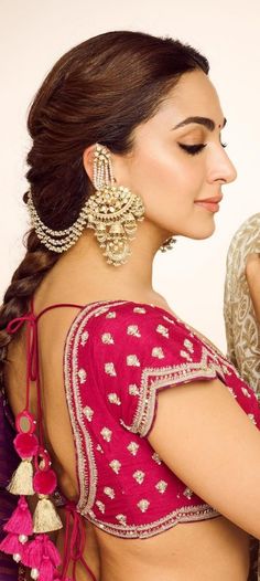 a woman in a pink sari with earrings on her head and the back of her body