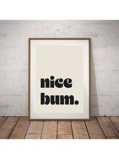 a black and white poster with the words nice bum on it, against a brick wall