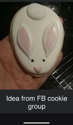 a close up of a person's hand holding a cookie with bunny ears on it