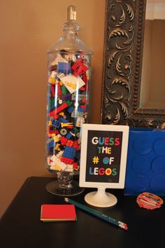 a glass jar filled with legos sitting on top of a table next to a sign