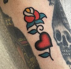 a skull and rose tattoo on the left arm with a red heart in front of it