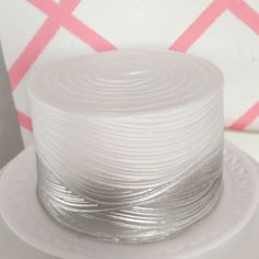 a white cake sitting on top of a table next to a pink and white wall