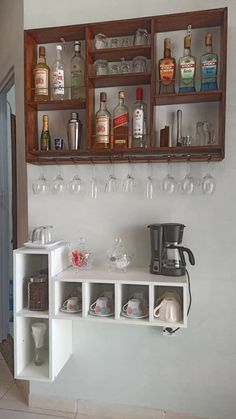 there is a shelf with wine glasses and cups on it, next to a coffee maker