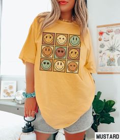 Our Comfort Colors retro smiley face graphic tee features a vintage inspired Fall colored happy face grid design. Our crewneck pairs perfectly with other matching size and style variations (linked below). ✩ ✩ 𝗧𝗼𝗱𝗱𝗹𝗲𝗿 𝗕𝗲𝗹𝗹𝗮 𝗖𝗮𝗻𝘃𝗮𝘀 𝗧𝗲𝗲: https://starrieapparel.etsy.com/listing/1765169455 ✩ 𝗞𝗶𝗱𝘀 𝗕𝗲𝗹𝗹𝗮 𝗖𝗮𝗻𝘃𝗮𝘀 𝗧𝗲𝗲: https://starrieapparel.etsy.com/listing/1764842461 ✩ 𝗞𝗶𝗱𝘀 𝗖𝗼𝗺𝗳𝗼𝗿𝘁 𝗖𝗼𝗹𝗼𝗿𝘀 𝗧𝗲𝗲: https://starrieapparel.etsy.com/listing/1764827691 ✩ Casual Yellow Top With Retro Print, Casual T-shirt With Retro Print And Crew Neck, Casual Crew Neck T-shirt With Retro Print, Casual Retro Print Crew Neck T-shirt, Fun Short Sleeve Tops With Smiley Face, Trendy Short Sleeve Top With Smiley Face, Fun Smiley Face Tops, Yellow Cotton Top With Retro Print, Funny Smiley Face Crew Neck Tops