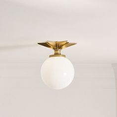 a ceiling light with a white ball hanging from it's center point in a room